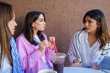 A group of young female friends laughing and enjoying their time together, chatting on a summer day in a café