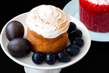 Easter cake on a white plate with Easter eggs on a black background