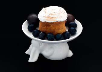 Easter cake on a white plate in the shape of an Easter bunny with Easter eggs on a black background