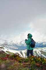 Girl hiker on a high point of the mountain looking down at the clouds and beautiful scenery