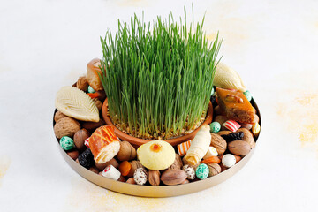 Traditional Azerbaijan holiday Novruz background with green semeni,traditional azerbaijan sweets,shekerbura,qogal,paxlava,mutaki and different nuts and sweets,top view,space for copy
