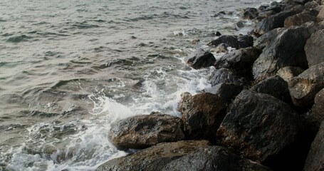 Sea waves hit large rocks on the coast, foaming and splashing as they wash over the boulders. 4k video, red komodo