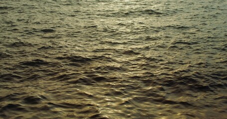 The dim light of the setting sun is reflected in the sea water. Light waves on the surface of the sea. The video was filmed in the evening. 4k video, red komodo