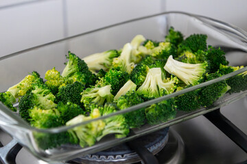 Fresh Broccoli Florets in a Glass Baking Dish on a Gas Stove