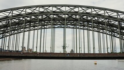 Obraz premium Drone video, view of the railway-pedestrian bridge in the city of Cologne. Many people across the wide river Rhine on a beautiful bridge. Drone video from the direction of the river.