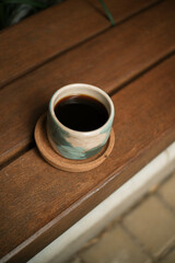 ceramic cup containing coffee with wooden coaster