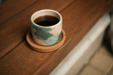 ceramic cup containing coffee with wooden coaster