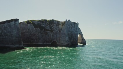 Fototapeta premium Picturesque natural rocks on the banks of the English Channel, forming a natural arch. Drone video from the sea. Lots of people on top of the cliff. Etretat, France