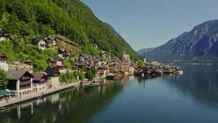 Fototapeta premium Panoramic view of the picturesque Austrian village of Hallstatt, located on the lake at the foot of the green Alpine mountains. Drone video, Austria