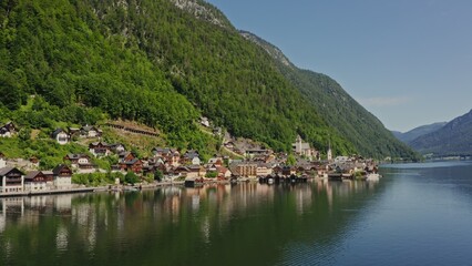 Fototapeta premium Panoramic view of the picturesque Austrian village of Hallstatt, located on the lake at the foot of the green Alpine mountains. Drone video, Austria