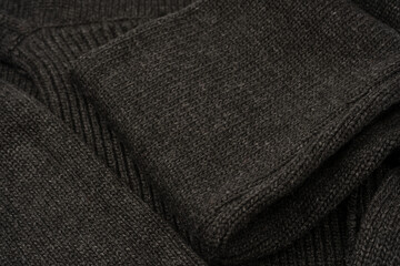 Dark grey sweater texture as a background. Knitted pattern.