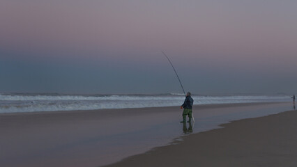 Fishing on beach at sunset