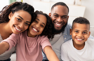 Portrait of african american family taking a selfie together at home indoors. Happy parents posing...