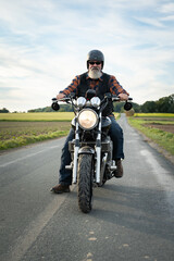 Motorräder - kultiger Biker fährt auf seinem Motorrad eine Landstrasse entlang, labelfrei und...