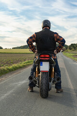 Motorradfahrer auf seiner Maschine von hinten, labelfrei und retuschiert.
