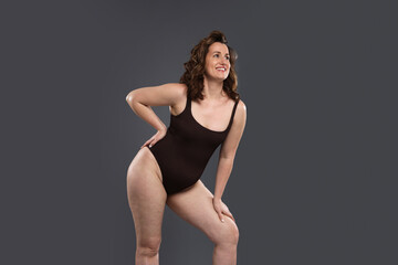 Beautiful woman in bodysuit on dark grey background. Cellulite problem