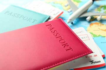 Passports in color covers, flight tickets and plane model on world map, closeup