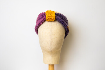 Crochet head band with a white background on a head display stand 