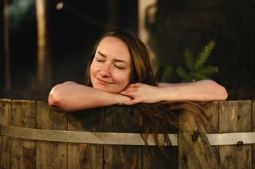 Relaxing woman enjoys soothing hot bath under the stars during winter holiday evening in the...