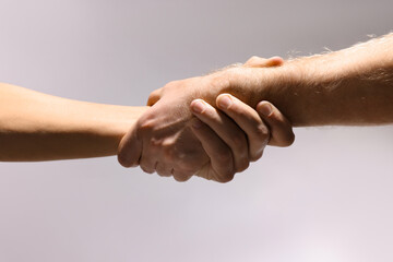 Fototapeta premium Help and support. People holding hands on light grey background, closeup