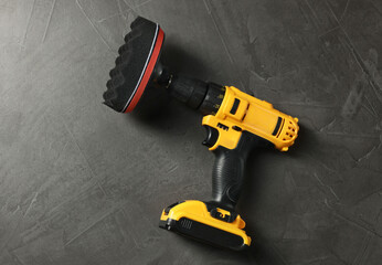 Electric screwdriver with polish pad on grey table, top view