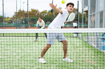Male player ready to hits the ball while playing padel on a hard court