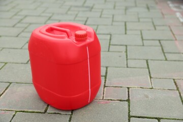 One red plastic canister on pavement outdoors, space for text