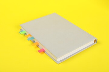Fototapeta premium Book with colorful tabs on yellow background, closeup