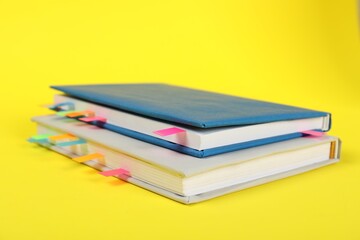 Books with colorful tabs on yellow background, closeup