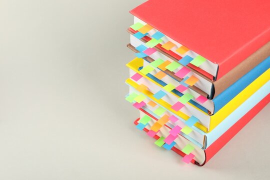 Books with colorful tabs on light gray background, closeup. Space for text