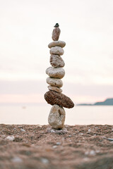 Cairn stands on the seashore at pink sunset