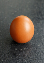 one brown chicken eggs on a black wooden background.