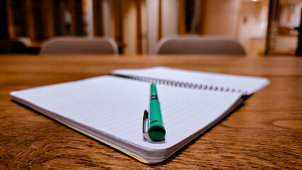 Open lined notebook and ballpoint pen on wooden table for study concept