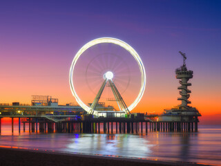 The Hague, Netherlands. Sea pier and Ferris wheel. Famous place on the beach in Holland. Seashore during sunset. Beach for relaxation. Photo for background, wallpaper, postcards.