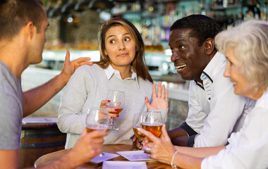 Diverse group having an awkward conversation at a bar with beer..