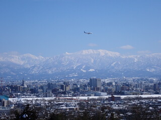 2025年2月25日雪景色の富山市街地と冠雪の北アルプ氏と旅客機