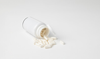 Mockup of a white bottle of medicine capsules, or food supplement, lying down on white background with copyspace
