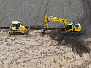 aerial view of an excavator and bulldozer at work on a construction site, road construction, earthworks, development