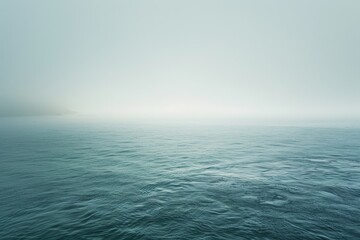 Obraz premium A tranquil seascape with a misty veil shrouding the horizon on a calm morning, Misty veil shrouding the horizon