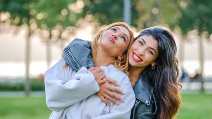 Fototapeta premium A young brunette woman posing and having fun with her mother in a grassy park on a summer day