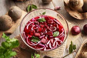 Preparation of fermented beet kvass in a glass bowl with fresh beetroot, onions, garlic and spices