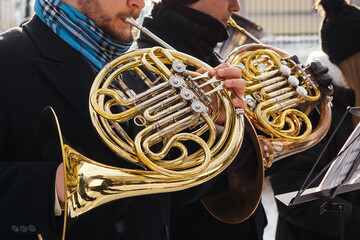 Talented musicians perform an elegant outdoor brass concert, playing French horns with skill and passion, creating a mesmerizing symphony of golden melodies.