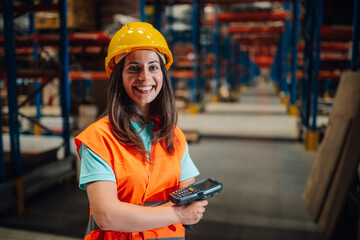 Smiling female warehouse worker holding barcode scanner in distribution center