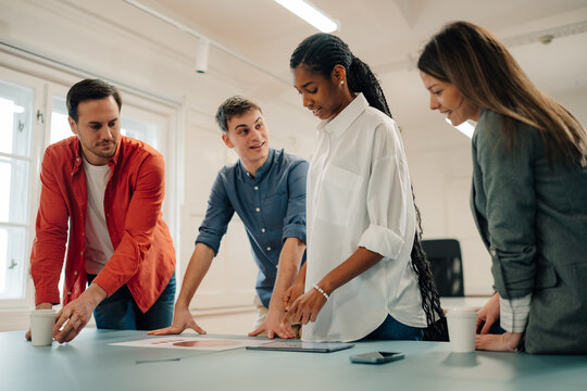 Marketing team analyzing charts and digital tablet during meeting