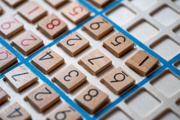 closeup hands carefully placing number into Sudoku puzzle, senior man focused on solving puzzle on...