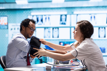 Physician doing a medical consultation with blood pressure monitor, taking pulse and heartbeat...