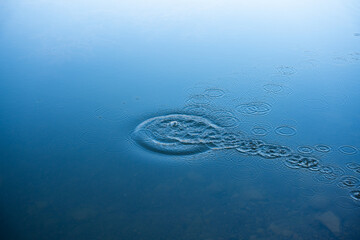 Circular water ripples and bubbles effect. Water ripples and round droplets on blue sea texture pattern background. Liquid motion on calm lake surface. Ring affect, circles