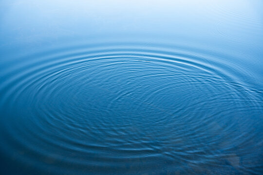Circular water ripples and bubbles effect. Water ripples and round droplets on blue sea texture pattern background. Liquid motion on calm lake surface. Ring affect, circles