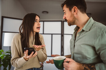 Jealous man spying his wife mobile phone while she is reading message