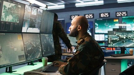 Man looking at screens in military HQ base housing operational missile defense system designed to intercept ballistic rockets. Special forces expert using tracking gear and radar systems, camera B